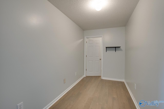 empty room with light wood-type flooring and a textured ceiling