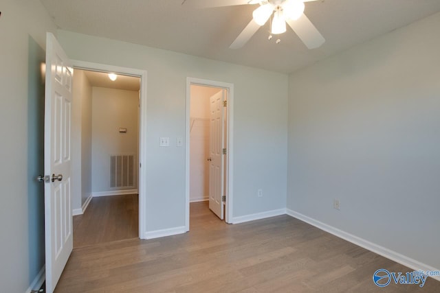 unfurnished bedroom with ceiling fan, light wood-type flooring, a spacious closet, and a closet