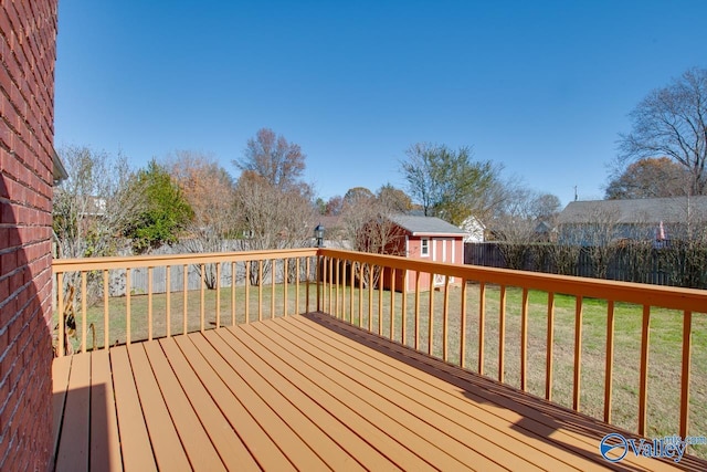 wooden terrace with a storage unit and a lawn