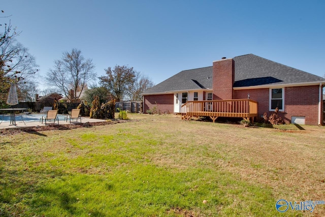 rear view of house with a yard, a patio area, and a pool side deck