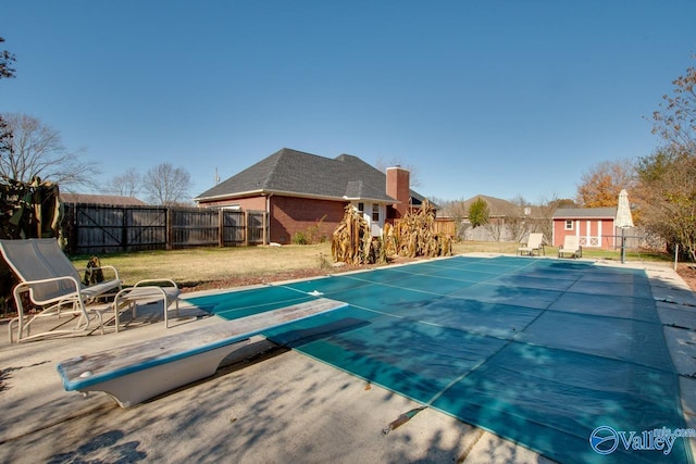 view of swimming pool with a yard, a shed, a diving board, and a patio area