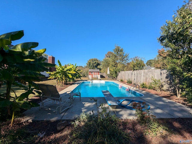 view of swimming pool featuring a diving board and a patio