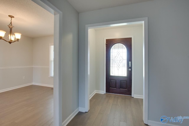 entryway featuring light hardwood / wood-style flooring, a chandelier, and a textured ceiling