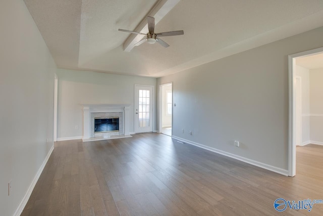 unfurnished living room with ceiling fan, a premium fireplace, a textured ceiling, and light wood-type flooring