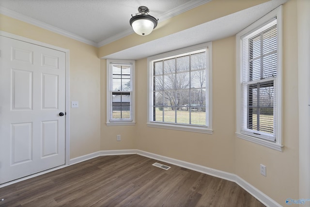 spare room featuring baseboards, visible vents, dark wood finished floors, ornamental molding, and a textured ceiling