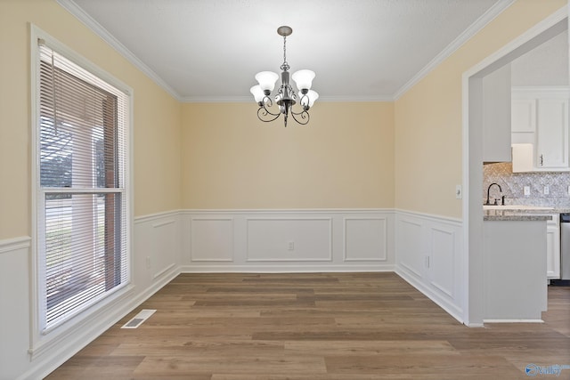 unfurnished dining area with wood finished floors, a healthy amount of sunlight, visible vents, and a chandelier