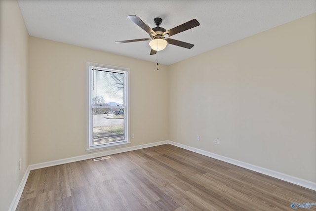 spare room with visible vents, ceiling fan, baseboards, and wood finished floors