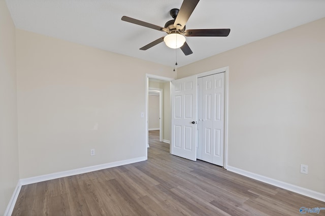 unfurnished bedroom with a closet, ceiling fan, baseboards, and wood finished floors