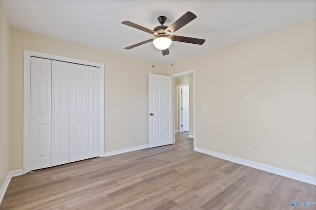 unfurnished bedroom with light wood finished floors, a closet, baseboards, and a ceiling fan