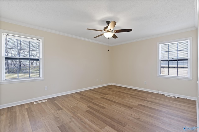 empty room with a ceiling fan, visible vents, light wood-style flooring, ornamental molding, and a textured ceiling