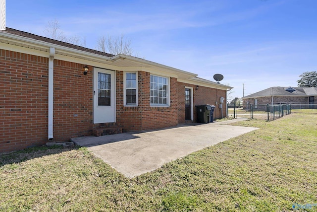 back of house featuring a patio, a gate, fence, a yard, and brick siding