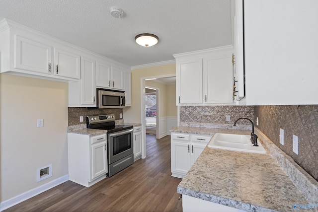 kitchen with a sink, light countertops, appliances with stainless steel finishes, white cabinetry, and dark wood-style flooring