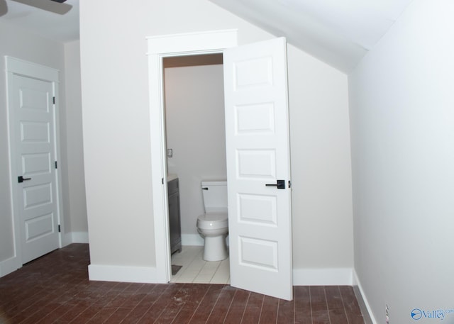 bathroom with hardwood / wood-style flooring, vanity, toilet, and lofted ceiling