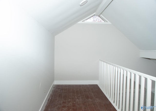 additional living space featuring vaulted ceiling with beams and dark wood-type flooring