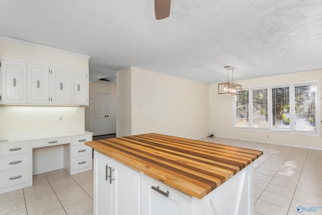 kitchen featuring wooden counters, pendant lighting, white cabinetry, and light tile patterned flooring