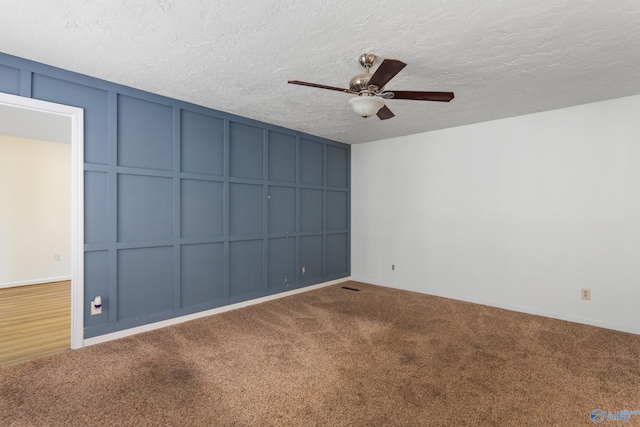 empty room with carpet flooring, ceiling fan, and a textured ceiling