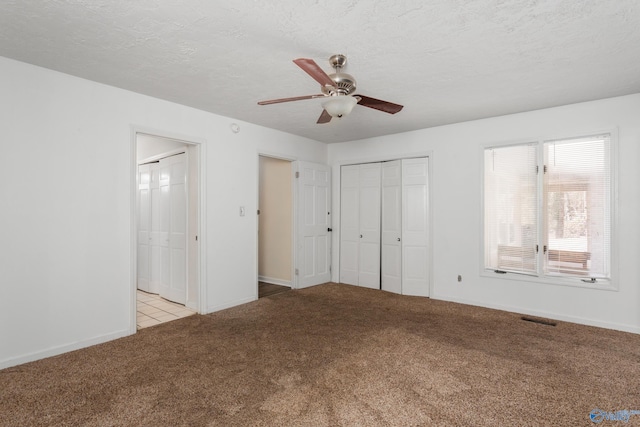 unfurnished bedroom featuring a textured ceiling, ceiling fan, and light carpet