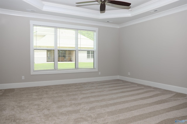 empty room featuring ornamental molding, light colored carpet, ceiling fan, and a tray ceiling