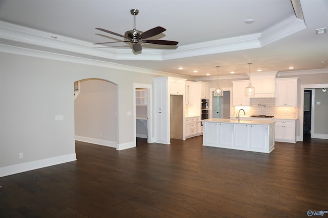 unfurnished living room featuring a raised ceiling, crown molding, dark hardwood / wood-style floors, and ceiling fan