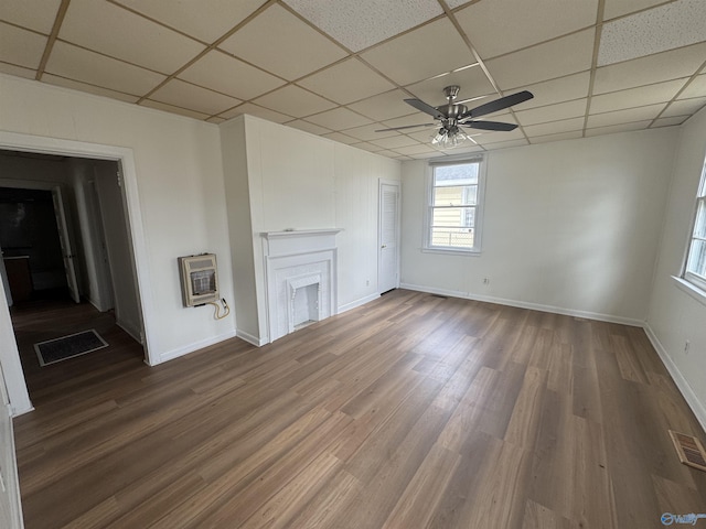 unfurnished living room featuring a paneled ceiling, visible vents, heating unit, and wood finished floors