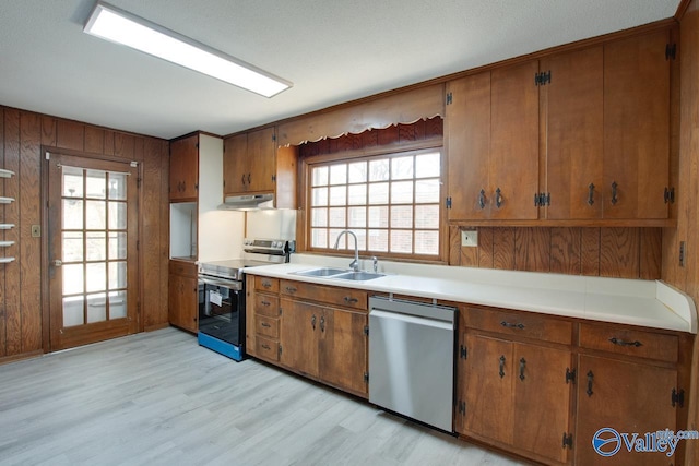 kitchen featuring brown cabinets, appliances with stainless steel finishes, a sink, and under cabinet range hood