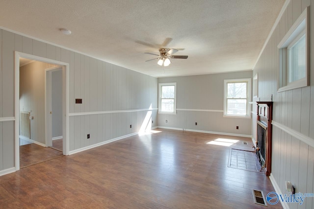 unfurnished living room with a wealth of natural light, a fireplace, wood finished floors, and visible vents