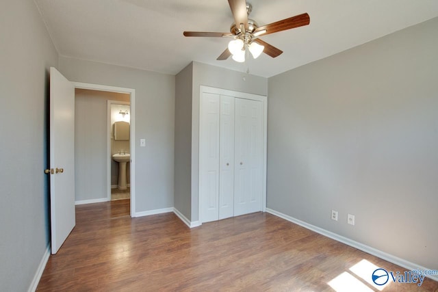 unfurnished bedroom with a sink, a closet, baseboards, and wood finished floors