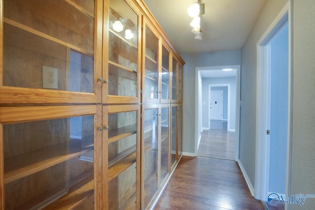 corridor with baseboards and dark wood-type flooring