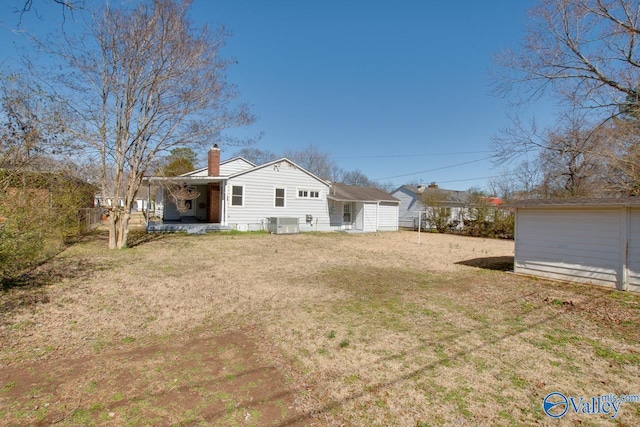 back of house with central AC unit, a chimney, fence, and a yard