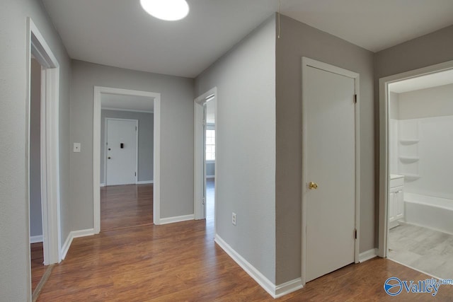 corridor with baseboards and wood finished floors