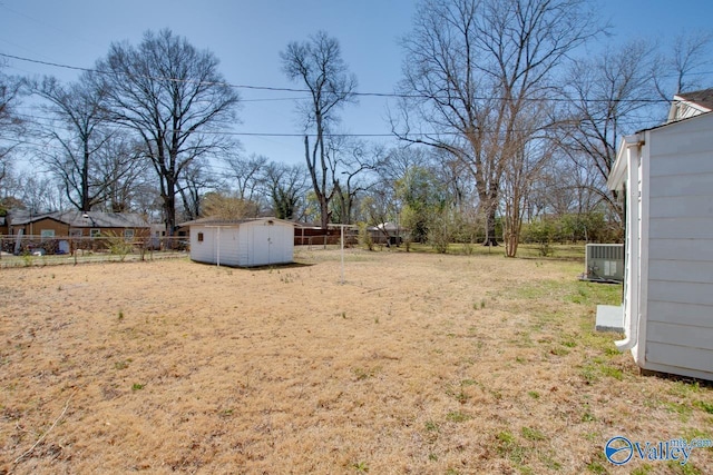 view of yard with an outbuilding, fence, a storage shed, and central AC unit