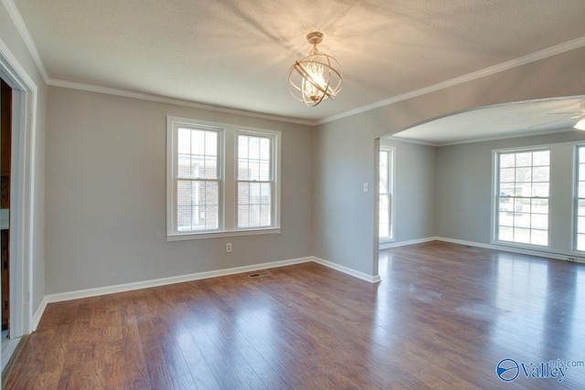 unfurnished room with baseboards, arched walkways, dark wood-style floors, a textured ceiling, and crown molding