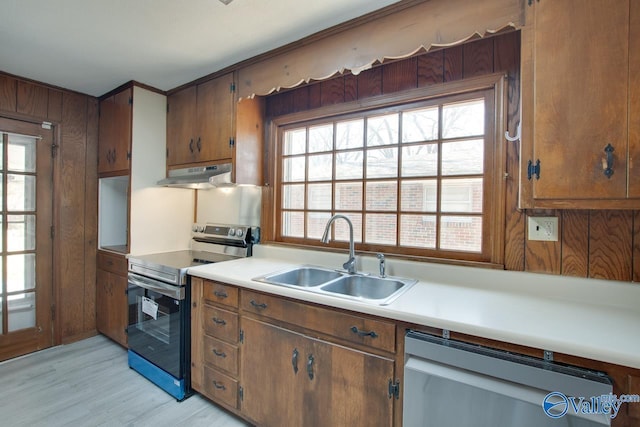 kitchen with light countertops, light wood-style flooring, appliances with stainless steel finishes, a sink, and under cabinet range hood