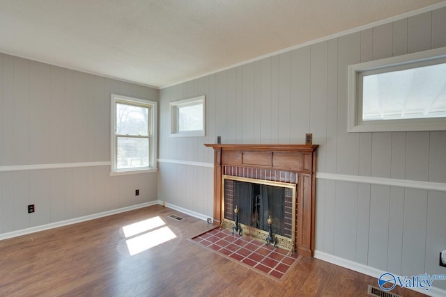 unfurnished living room with ornamental molding, a fireplace, baseboards, and wood finished floors