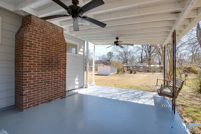 view of patio / terrace featuring an outbuilding, ceiling fan, a storage unit, and fence