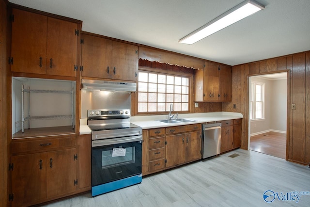 kitchen featuring stainless steel appliances, a healthy amount of sunlight, a sink, and under cabinet range hood