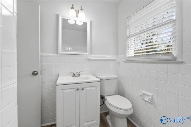 bathroom with vanity, toilet, and tile walls