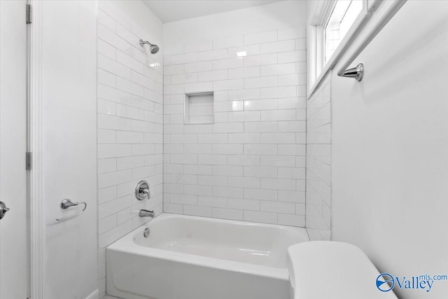 bathroom with toilet and tiled shower / bath