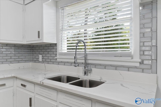 kitchen with backsplash, white cabinetry, sink, and plenty of natural light