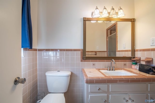 bathroom with vanity, toilet, and tile walls