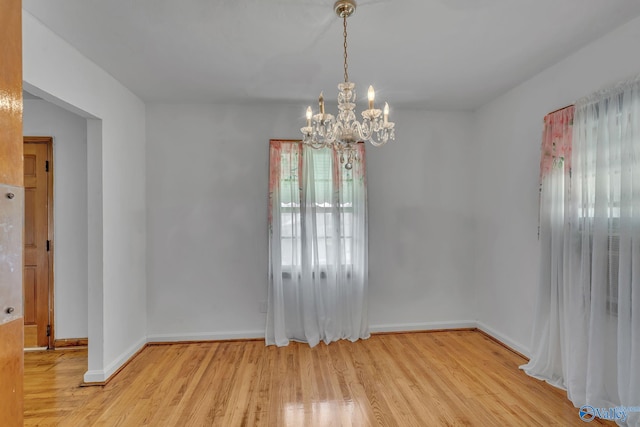 unfurnished dining area featuring light wood-type flooring and a chandelier