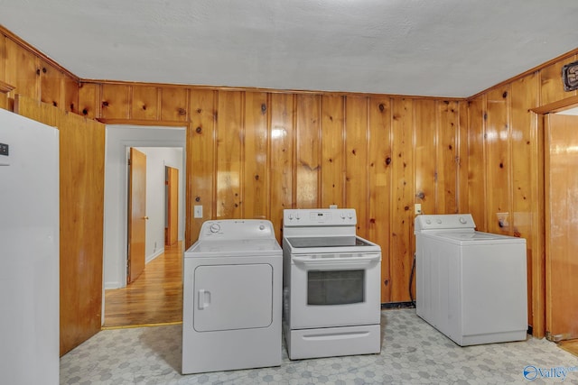 laundry room featuring separate washer and dryer, a textured ceiling, and wooden walls