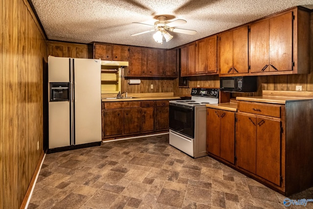 kitchen featuring sink, white appliances, wooden walls, and ceiling fan