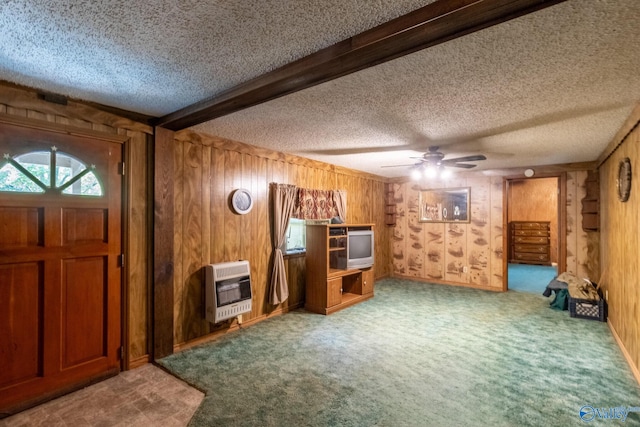 interior space featuring heating unit, wooden walls, ceiling fan, a textured ceiling, and beam ceiling