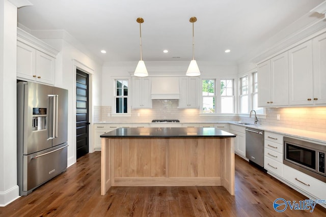kitchen featuring premium range hood, appliances with stainless steel finishes, decorative backsplash, and white cabinets