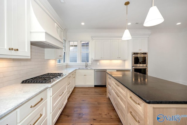 kitchen with a sink, custom exhaust hood, decorative backsplash, a kitchen island, and appliances with stainless steel finishes