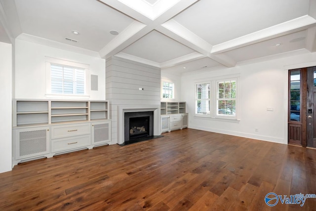 unfurnished living room featuring a fireplace, beam ceiling, plenty of natural light, and dark wood-type flooring