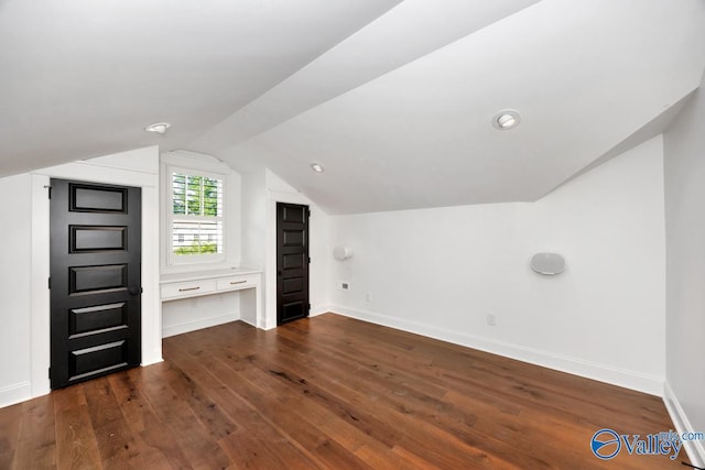 additional living space featuring baseboards, dark wood-style floors, and vaulted ceiling