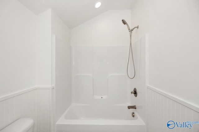 full bath featuring toilet, tub / shower combination, a wainscoted wall, and vaulted ceiling