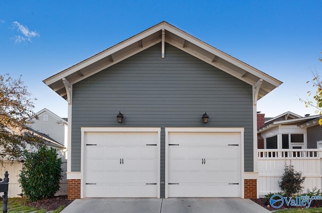 garage featuring concrete driveway and fence